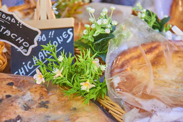 Freshly baked Spanish bread and pastries wrapped in transparent film at a local Granada market, decorated with small flowers and signs. bakery tradition
