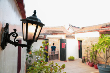 Street lamp in front of a blur Fujian-style house courtyard. Focus on the lamp.
