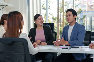 Business colleagues collaborating and discussing ideas around a table in a modern corporate office, showing teamwork and communication