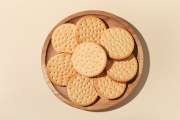 Wooden plate with tasty sandwich biscuits on beige background