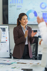 Asian businesswoman clapping hands, smiling with colleagues at an office meeting, celebrating...