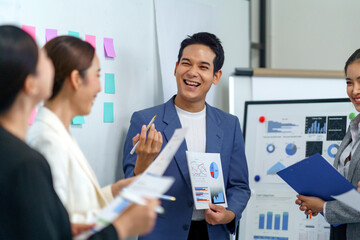 Asia business team having a productive meeting, collaborating and laughing while analyzing graphs and charts on paper and whiteboard