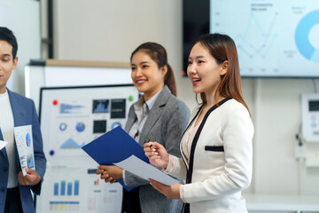 Asian business team in a modern office meeting, reviewing charts and data on screen while strategizing finance and marketing plans