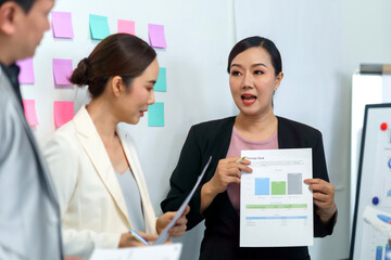 Asian businesswoman presenting financial data and savings goals to colleagues, collaborating on business strategy in a modern office