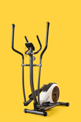 Modern exercising bike on yellow background