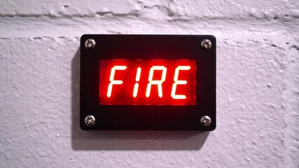 A close-up of a wall-mounted digital display showing the word "FIRE" in bright red - Powered by Adobe
