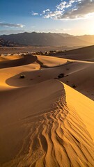 Winding sand dunes under setting sun with mountains