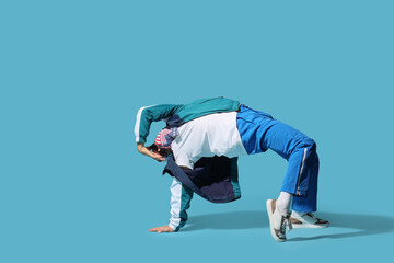 Young man dancing hip-hop on blue background