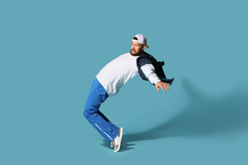 Handsome male hip-hop dancer dancing on blue background