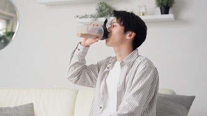 リビングでプロテインを飲むアジア人男性