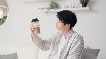 リビングでプロテインを見るアジア人男性