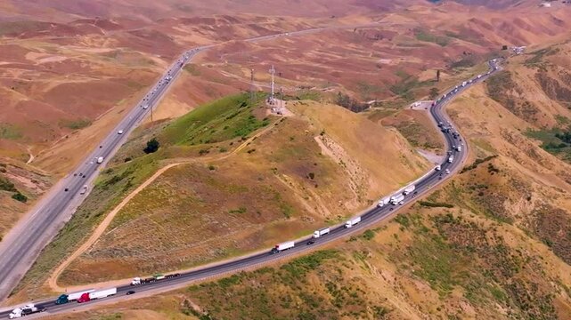 Ground-level 4K footage of Interstate 580 packed with semi-trucks and commuter traffic moving through Altamont Pass in Northern California. Ideal for illustrating freight transport, logistics operatio