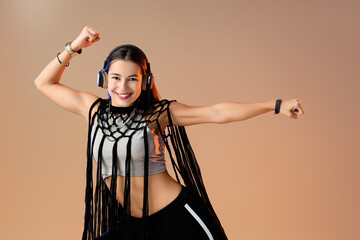 Female hip-hop dancer in headphones on beige background