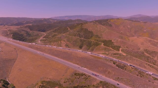 Ground-level 4K footage of Interstate 580 packed with semi-trucks and commuter traffic moving through Altamont Pass in Northern California. Ideal for illustrating freight transport, logistics operatio