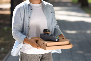 Male courier with pizza boxes, coffee and payment terminal outdoors