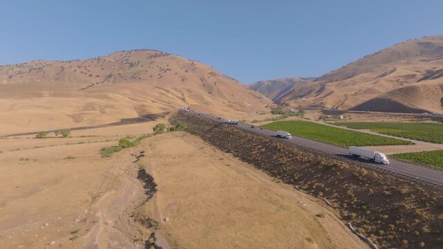 4K aerial shot showing multiple lanes of cars and trucks filling Interstate 5 near Grapevine Road at the north end of Tejon Pass. Highlights the scale and economic importance of California&rsquo;s primary n