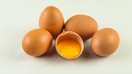 Group of brown raw eggs, one is broken, isolated white background
