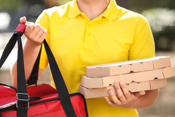 Male courier with pizza boxes and food bag outdoors, closeup