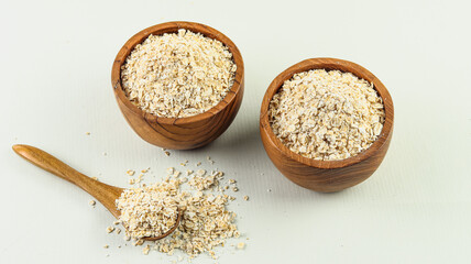 Dry oatmeal in two wooden bowls on a white background