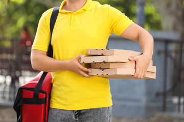 Male courier with food bag and pizza boxes outdoors