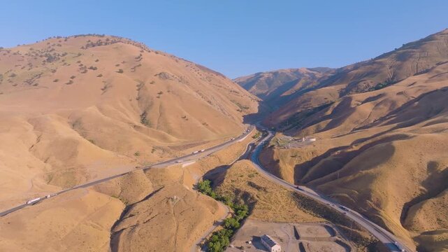 4K aerial shot showing multiple lanes of cars and trucks filling Interstate 5 near Grapevine Road at the north end of Tejon Pass. Highlights the scale and economic importance of California&rsquo;s primary n