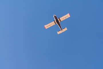 Small ultralight airplane with overhead wing and single propeller flying in sunset sky.