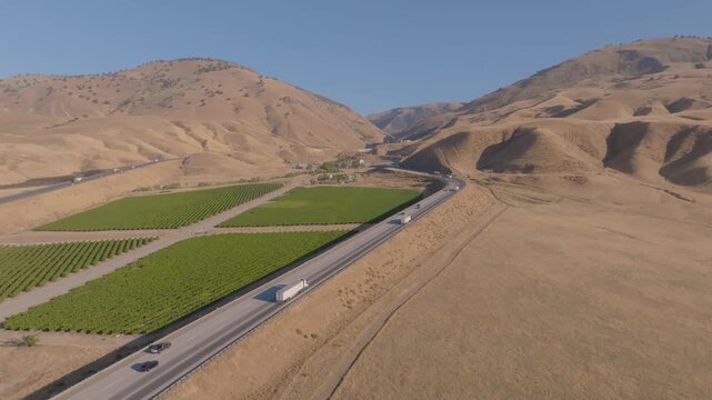 4K aerial shot showing multiple lanes of cars and trucks filling Interstate 5 near Grapevine Road at the north end of Tejon Pass. Highlights the scale and economic importance of California&rsquo;s primary n