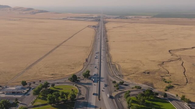 4K aerial shot showing multiple lanes of cars and trucks filling Interstate 5 near Grapevine Road at the north end of Tejon Pass. Highlights the scale and economic importance of California&rsquo;s primary n