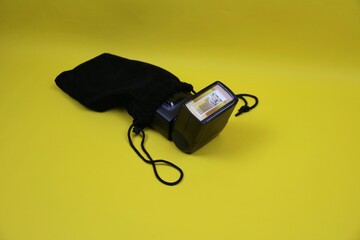 Compact Flash Unit With Black Pouch on Bright yellow Background for Studio Lighting