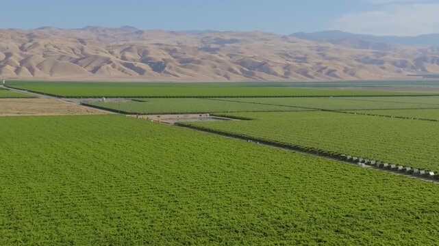 4K aerial drone footage of Interstate 5 running through California&rsquo;s Central Valley with farmland stretching on both sides and a water canal following the highway. Trucks and cars move steadily along 
