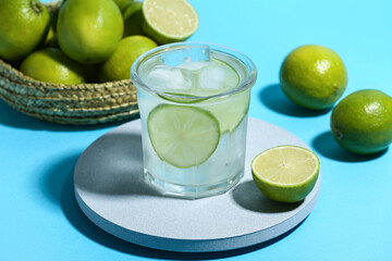 Decorative podium with glass of lime infused water on blue background
