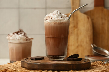 Glasses of cold cocoa drink with whipped cream and chocolate on white table