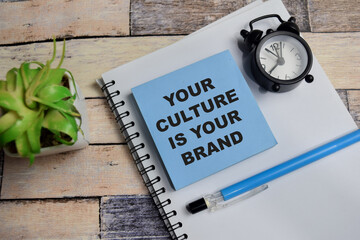 Concept of your culture is your brand write on sticky notes isolated on Wooden Table.