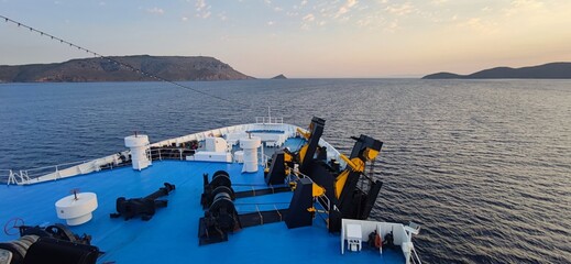 Bow of a large passenger ship sailing through a narrow strait between islands, capturing the beauty and precision of maritime navigation. © Politischios