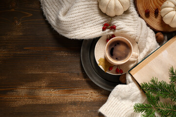 Composition with mug of tasty coffee, sweater and autumn decor on wooden background