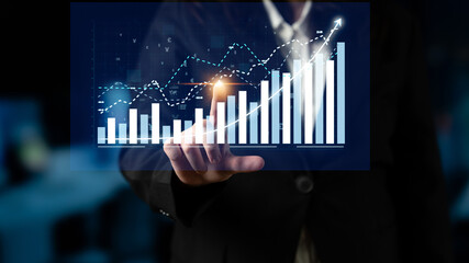 A business professional uses a digital interface to interact with a virtual financial graph,...