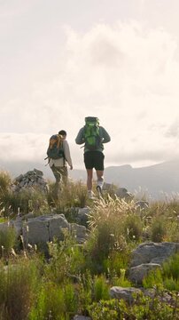 Back, couple and hiking on mountain for adventure date, tourist exploration and bonding together. People, trekking or walking in nature with backpack for connection, wellness or healthy relationship.