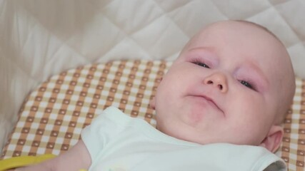  baby girl is lying on the bed and crying. The kid holds her toy.