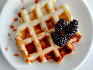 Waffle with pine cones jam on a white plate.