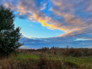 Sunset clouds painting bright sky over rural field