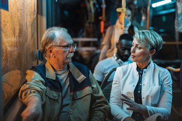 Senior man and woman having conversation on public bus at night