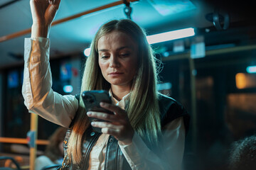 Woman commuting on bus at night using smartphone © PintoArt
