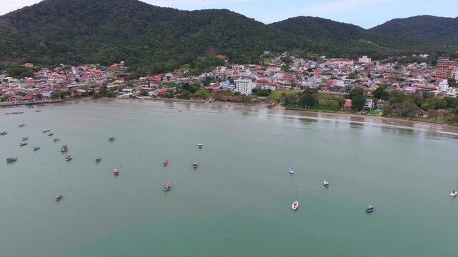 Smooth left-tracking drone glide over the ocean, revealing colorful boats docked at harbor.