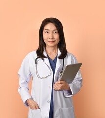 Portrait of asian female doctor in medical uniform with stethoscope on peach color background.
