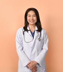 Portrait of asian female doctor in medical uniform with stethoscope on peach color background.
