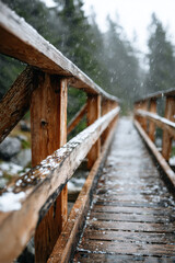 Snow falling on wooden bridge in mountain forest