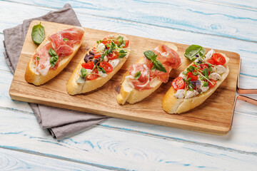 Tasty antipasto toasts featuring classic caprese with mozzarella and tomatoes, and savory prosciutto with herbs