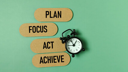 Four-Step Goal Process: Plan, Focus, Act, and Achieve Text Cards Next to a Small Alarm Clock on a...