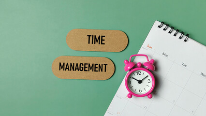 Time Management Concept with Pink Alarm Clock and Calendar on Green Background