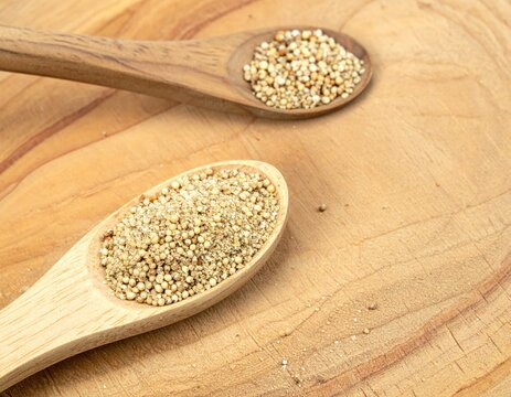 Close-up of two wooden spoons filled with small, light-colored grains
